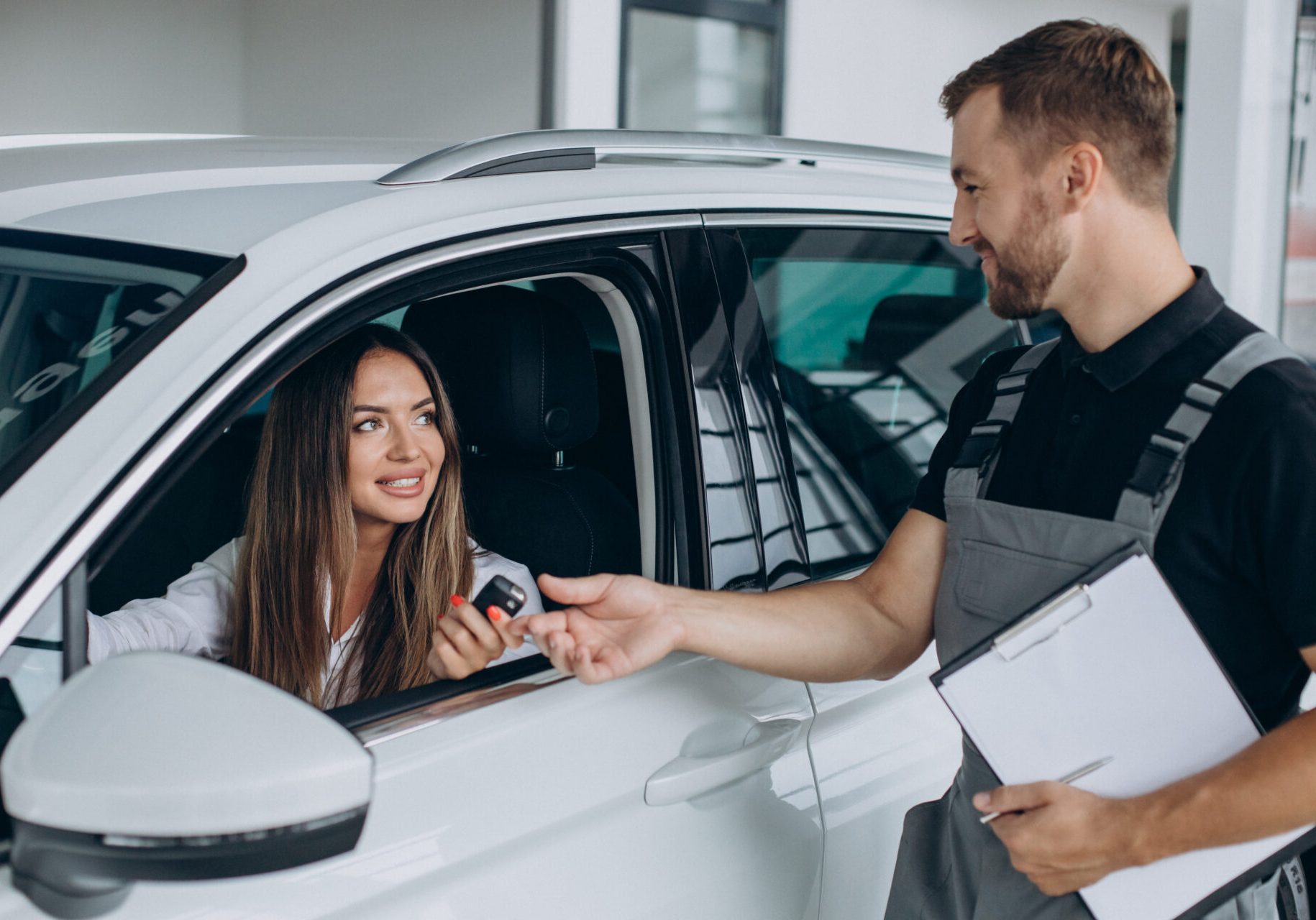 Woman at acr service station checking her car with mechanic
